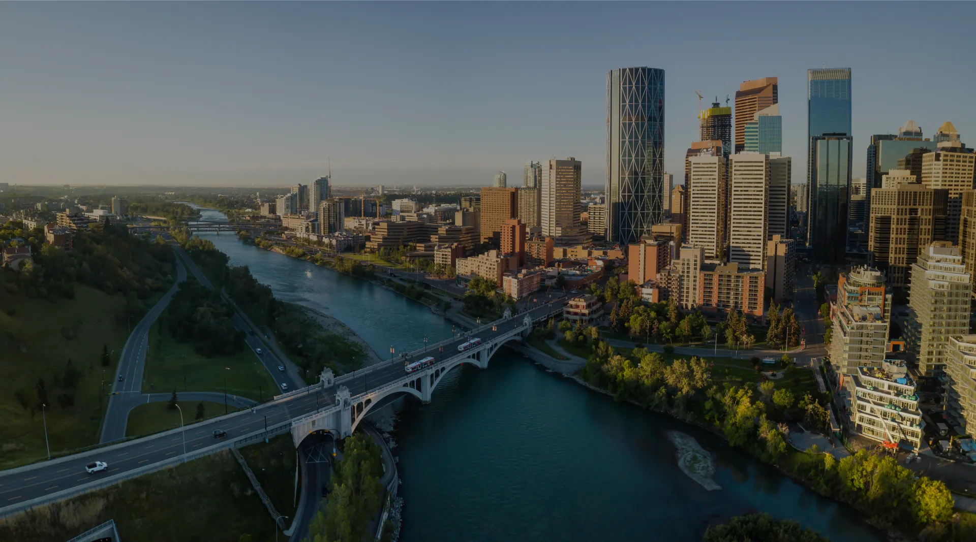 view of a city on the bank of a river, with a bridge crossing